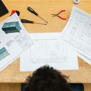 Reviewing technical drawings of display cases at the design desk