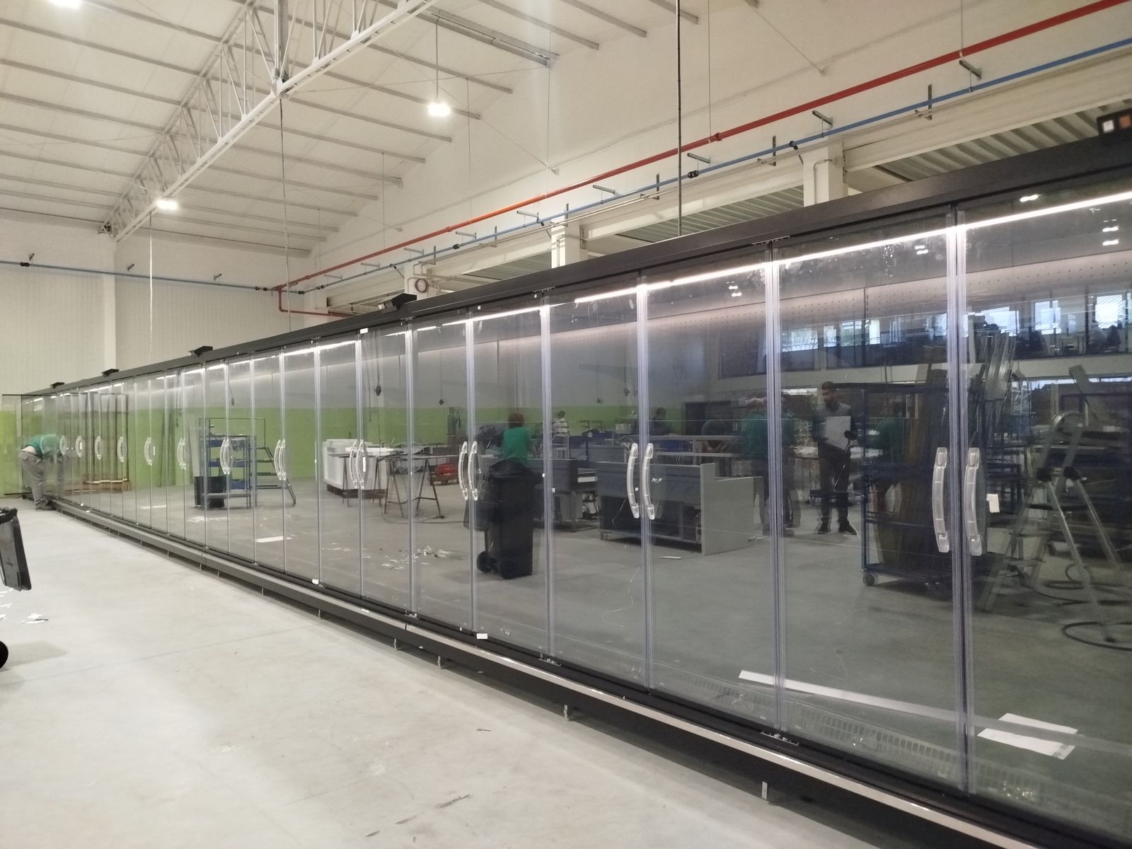 Long line of glass-door refrigerated display cases assembled on the production floor
